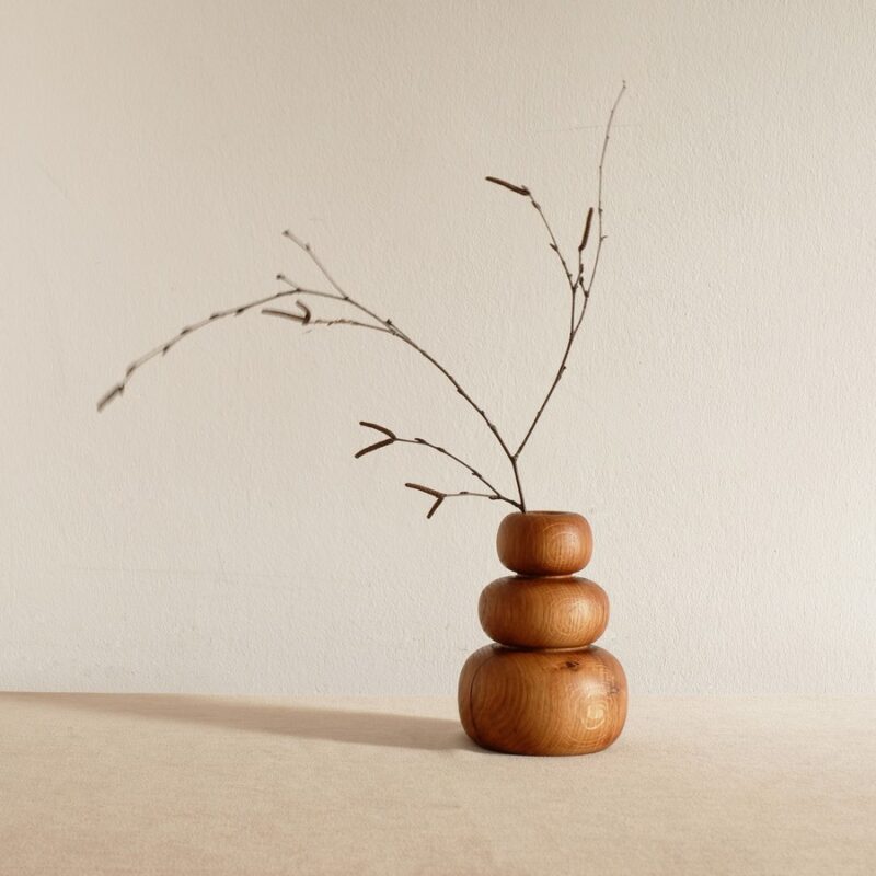 Florero de madera de roble torneado con una rama en su interior.